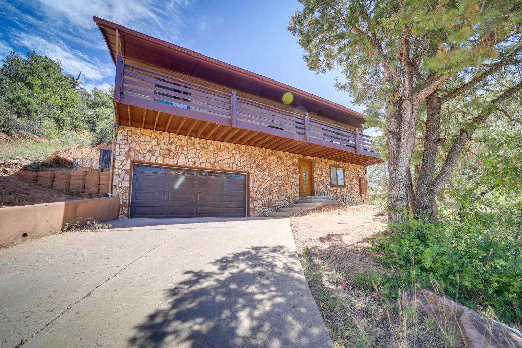 a house with a garage door and a tree at Payson Cabin with Deck Near Hiking, Fishing and More! in Payson