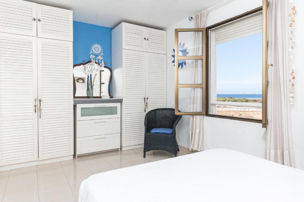 エル・メダノにあるLa casa de Montse Vivienda Vacacional Playa de la Tejitaのベッドルーム1室(ベッド1台、窓、椅子付)