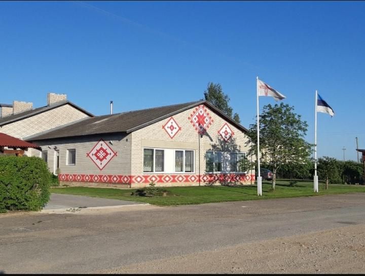 une maison avec deux drapeaux devant elle dans l'établissement Obinitsa Puhkemaja, à Obinitsa