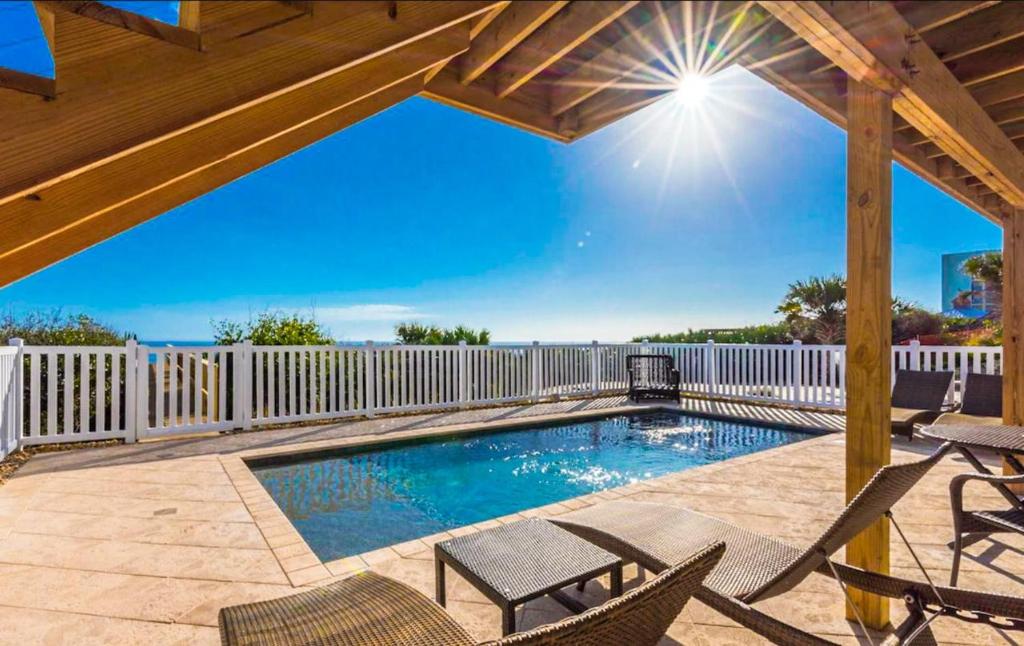 - une piscine avec des chaises et une clôture blanche dans l'établissement Ocean Dream, à New Smyrna Beach