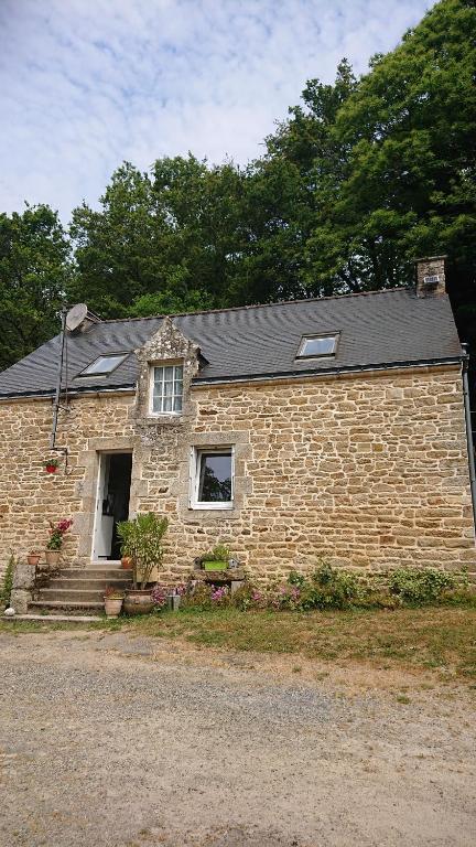 een stenen huis met een witte deur en ramen bij Le Moulin De Branféré. in Le Guerno