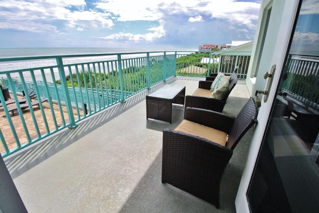 a balcony with two chairs and a view of the ocean at The Wave 302 in New Smyrna Beach