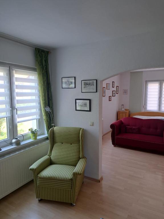 a living room with a green chair and a red couch at Ferienwohnung Rosengarten in Ballenstedt