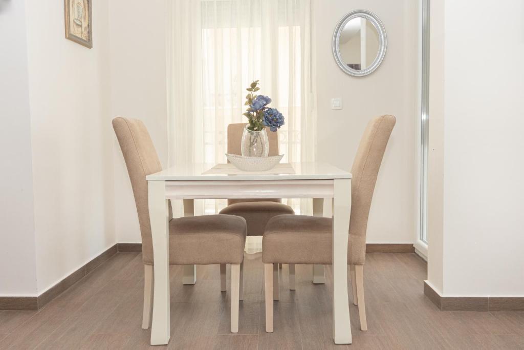 a white dining room table with chairs and a vase of flowers at Apartments Horizont in Budva