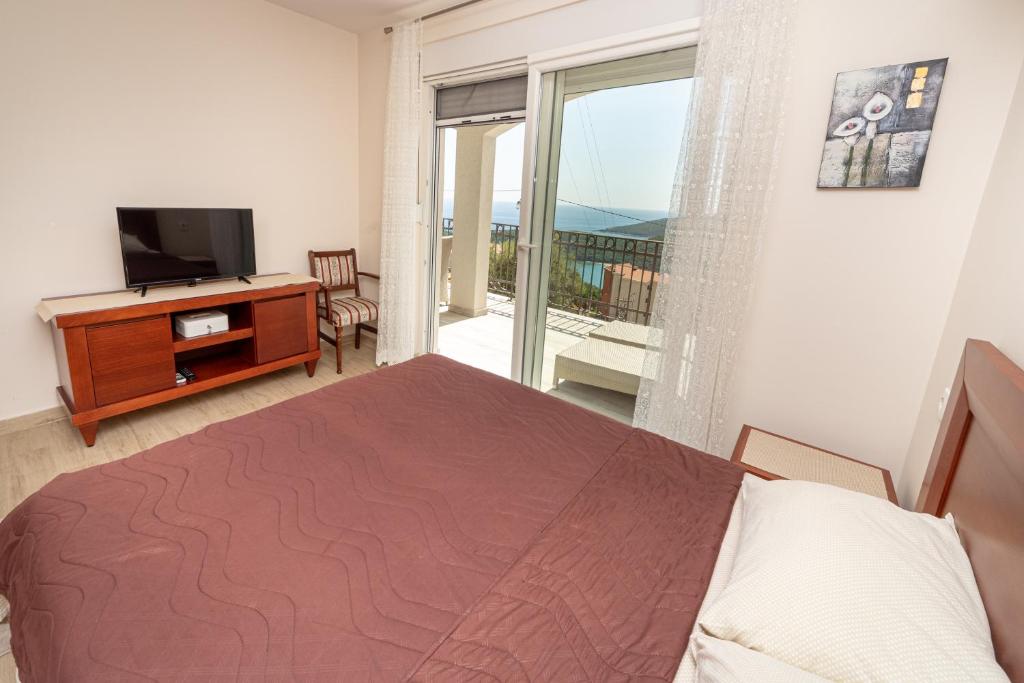 a bedroom with a bed and a television and a balcony at Apartments Horizont in Budva