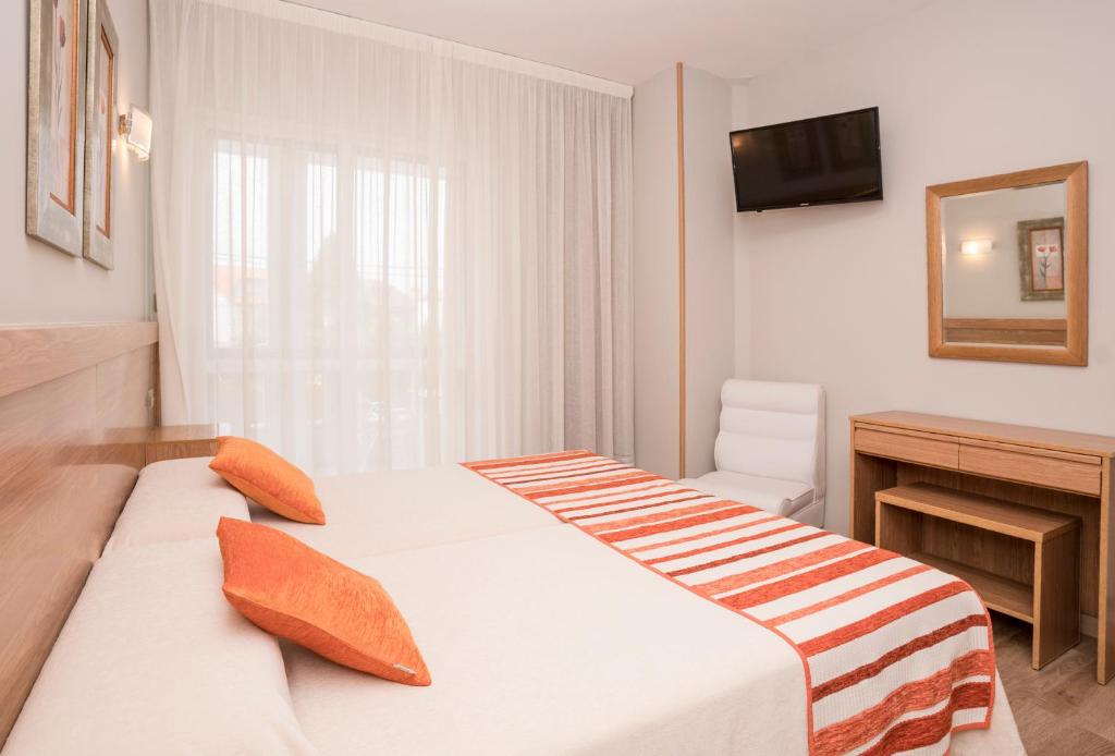 Habitación de hotel con cama y escritorio en Hotel Caribe Sanxenxo, en Sanxenxo