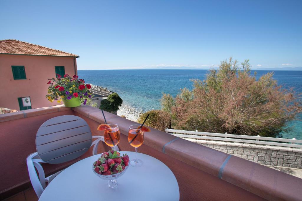 a table with two glasses on a balcony with the ocean at Hotel Sardi in Pomonte