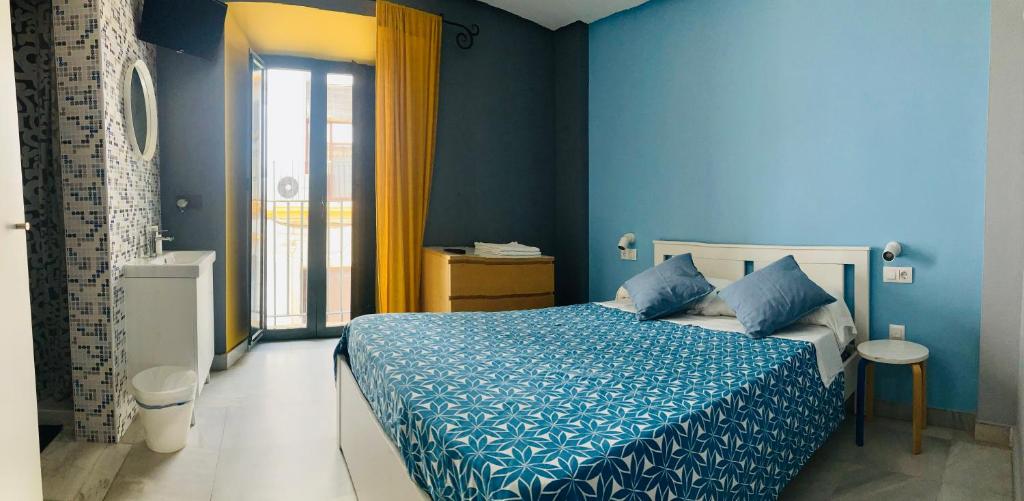エル・プエルト・デ・サンタマリアにあるHostal Baobabのベッドルーム1室(青い壁、青いシーツ付きのベッド1台付)