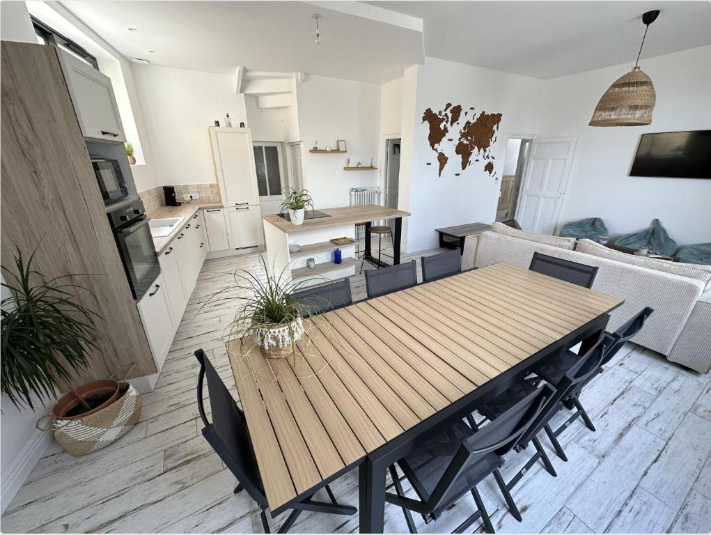 uma cozinha e sala de jantar com uma mesa de madeira e cadeiras em Jolie maison ételoise - mer , cœur d etel em Étel