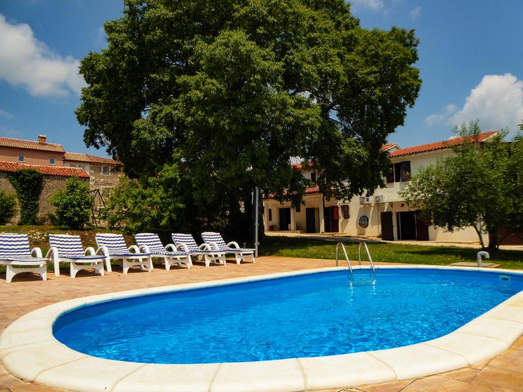 una piscina con tumbonas y un árbol en Casa istriana nona Pina, en Kaštelir