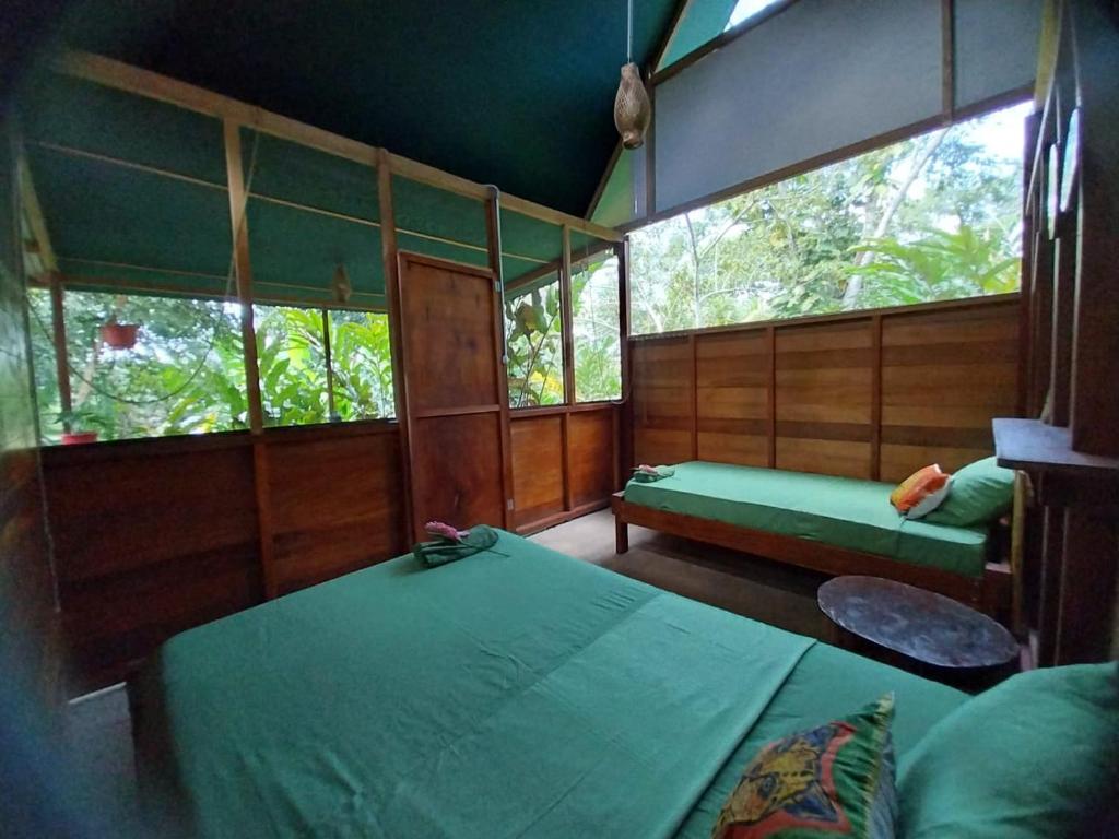 a room with two beds and a bench and windows at JARDIN DE LAS MUSAS in Puerto Maldonado