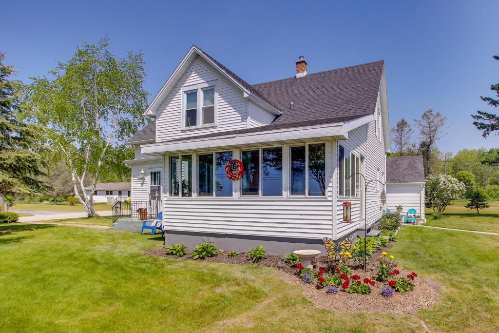 una casa bianca con fiori in un cortile di Two Rivers Thiede House - Walk to Lake Michigan! a Two Rivers
