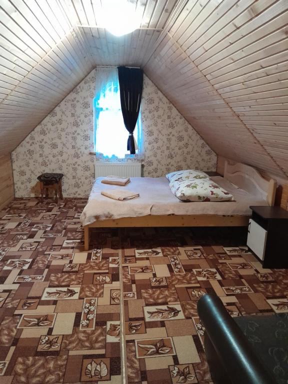 a bedroom with a bed and a floor with a window at Котеджі "У Яни" in Yablunytsya