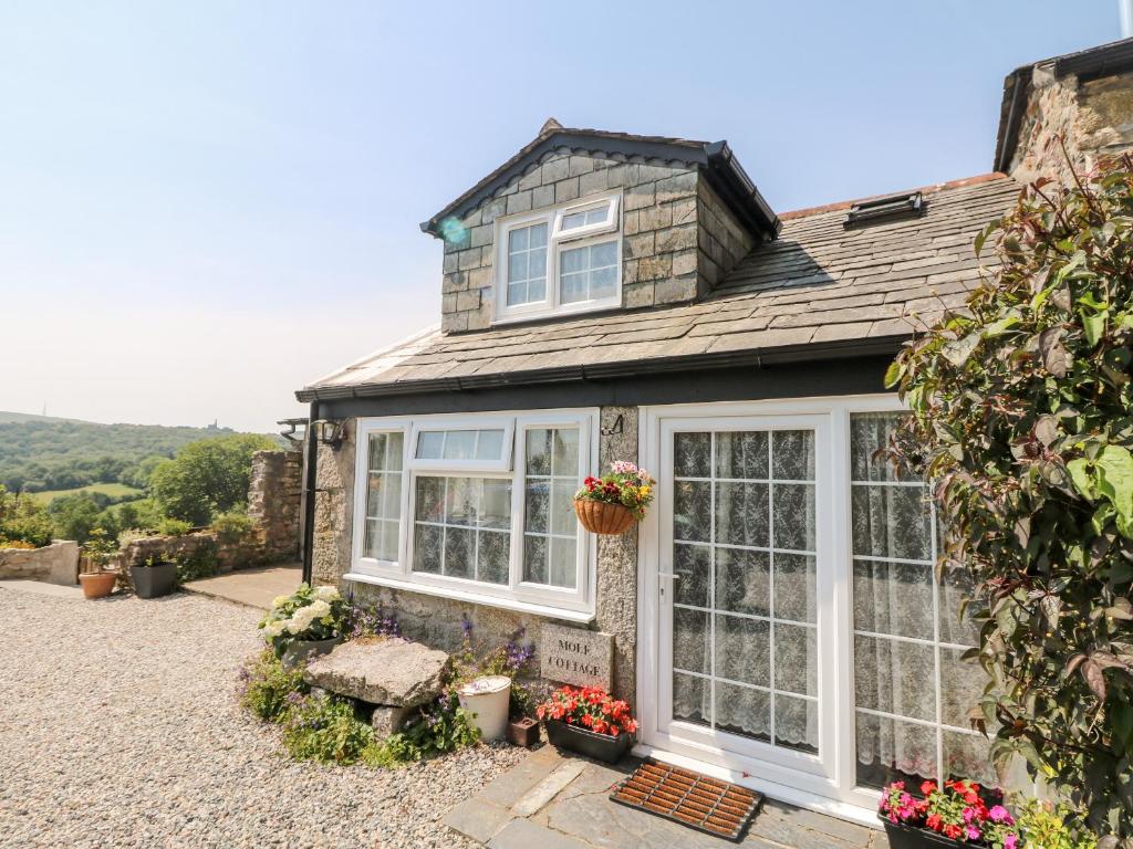 a house with white windows and flowers in the yard at Mole Cottage in Liskeard