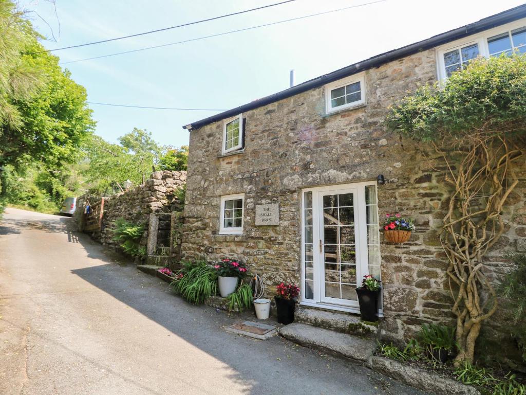 a stone house with flowers in front of it at Small Barn in Liskeard