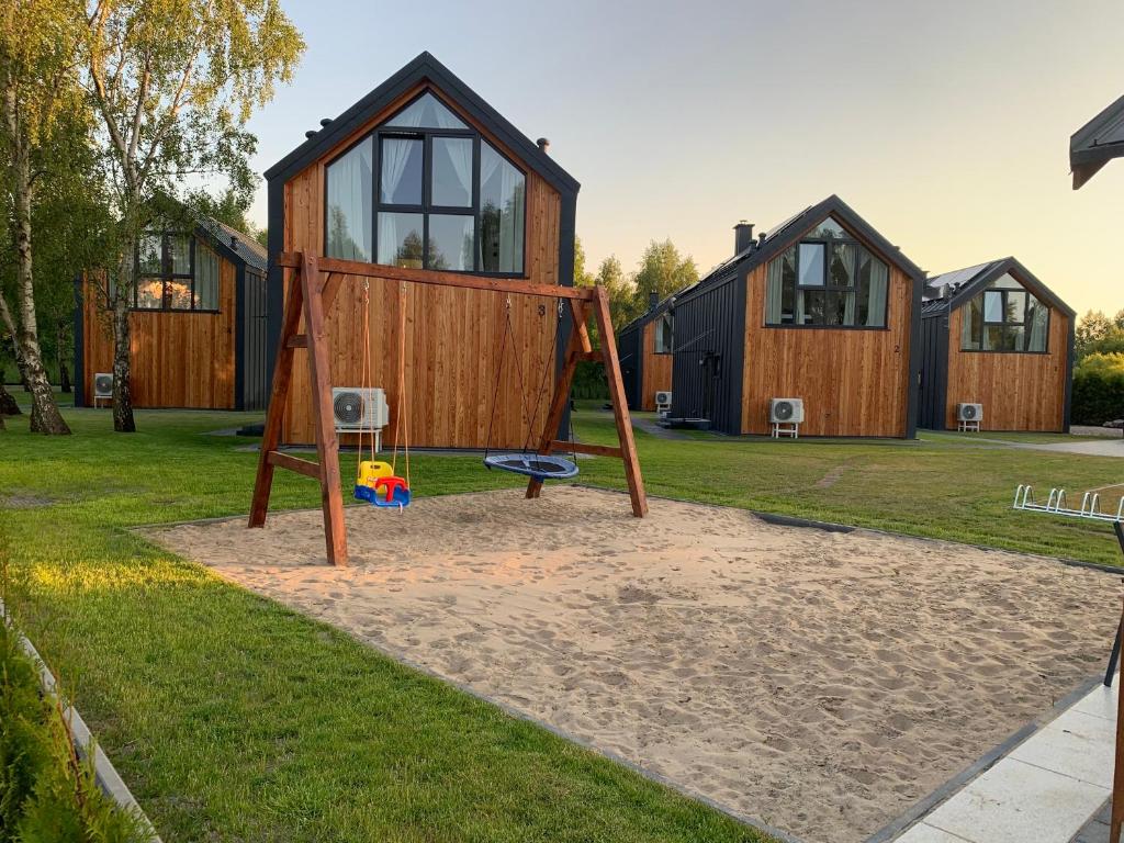 a tiny house with a swing and a playground at Baltic Homes Lubiatowo in Lubiatowo