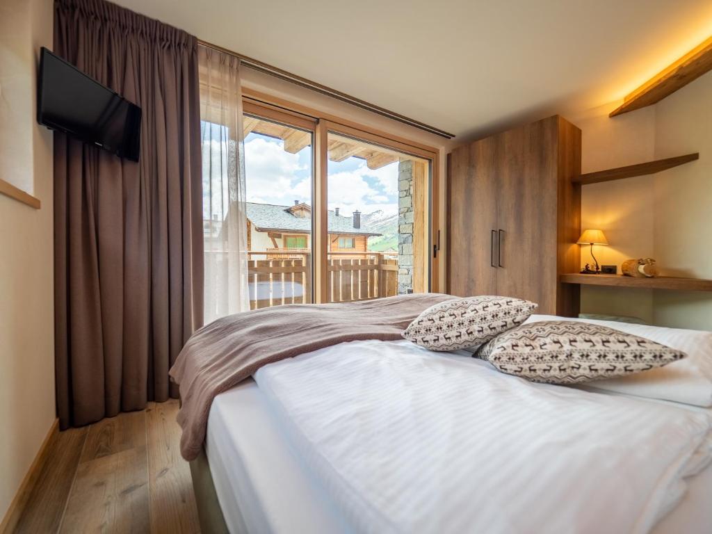 a bedroom with a bed and a large window at Deschana Lodge in Livigno