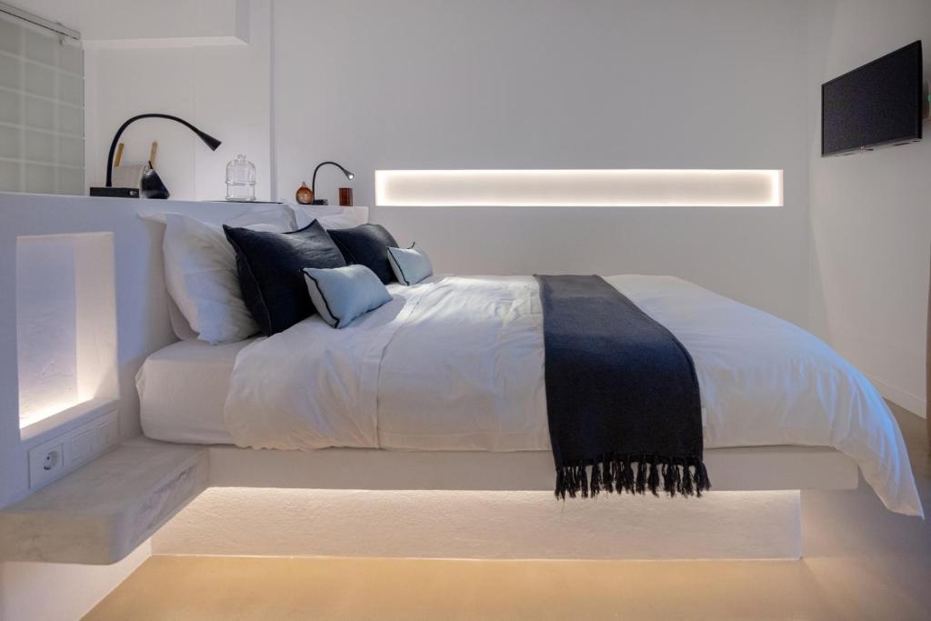 um quarto com uma cama branca e um cobertor preto e branco em SEAMENTO suites em Tinos