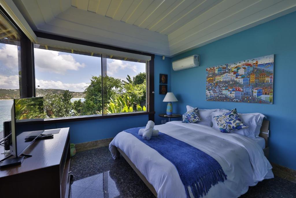 a blue bedroom with a bed and a large window at Cliffside Luxury Inn in Búzios