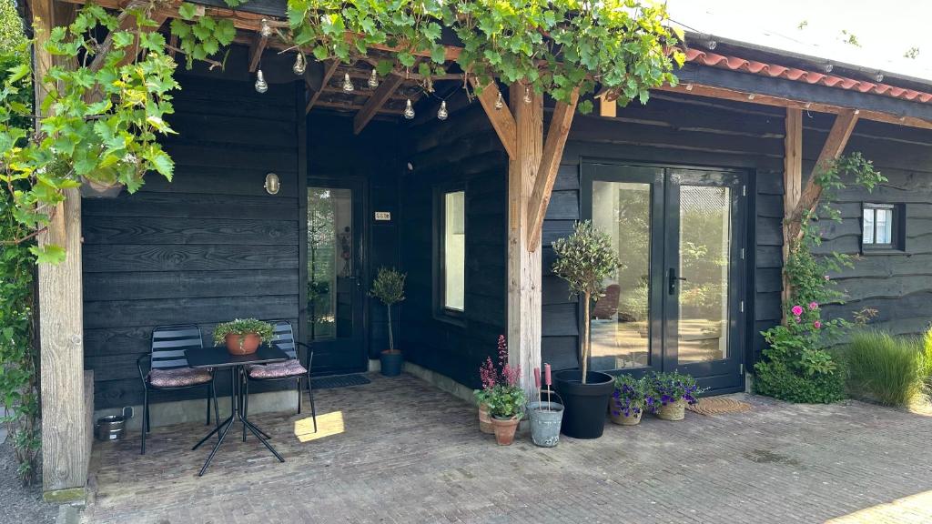 une terrasse couverte d'une maison avec une table et des plantes en pot dans l'établissement bedandbreakfastrouveen, à Rouveen