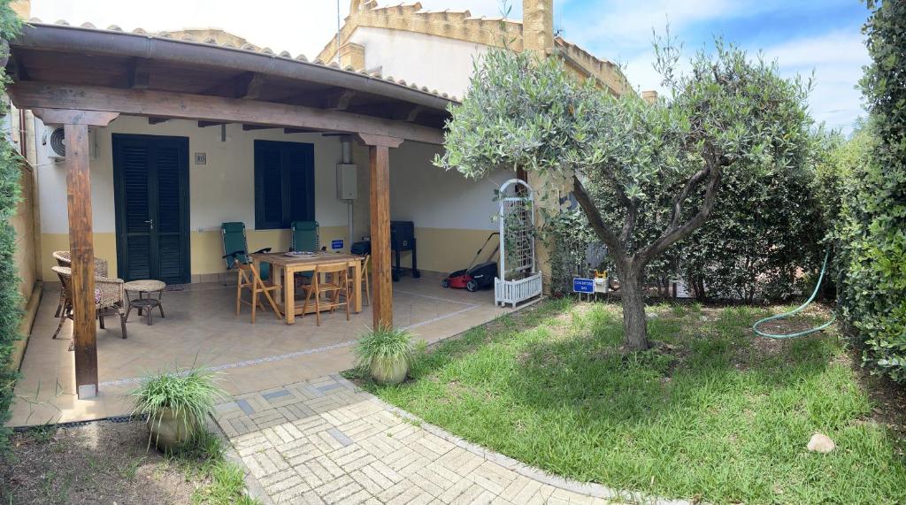 een patio met een tafel en een boom in een tuin bij Villetta sul mare in Resort Village in Campofelice di Roccella