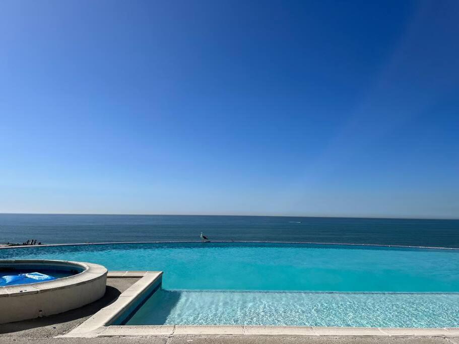a swimming pool with the ocean in the background at Calafia, Oceanview Condo Resort in Rosarito. in Rosarito