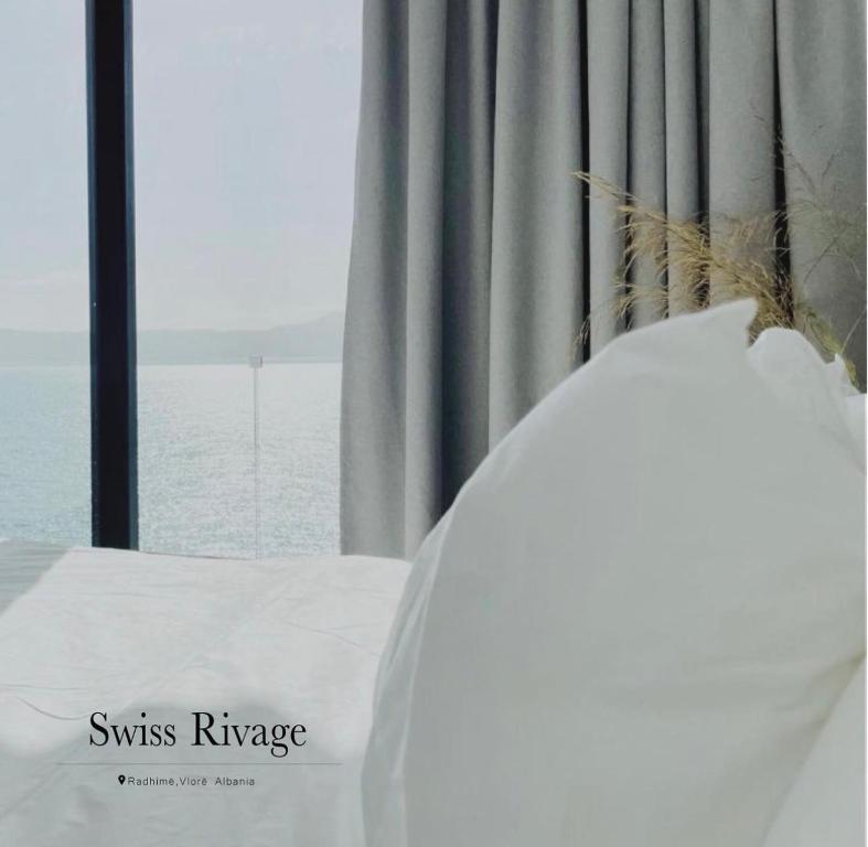 a bed in a room with a window with the ocean at Swiss Rivage Hotel in Vlorë