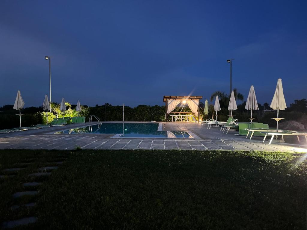 una piscina con tavoli e ombrelloni di notte di A Lu Fanizza a Cutrofiano