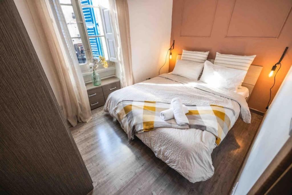 um quarto com uma cama com lençóis brancos e almofadas em Olivias em Qormi