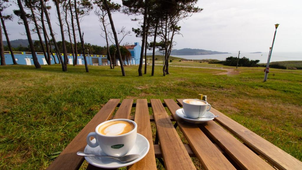 dos tazas de café sentadas en una mesa de madera en Glamping Atlántico, en Ferrol