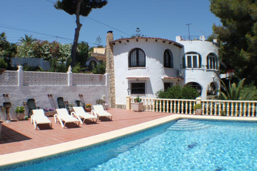 a villa with a swimming pool in front of a house at El Cisne - holiday home with private swimming pool in Benissa in Pedramala