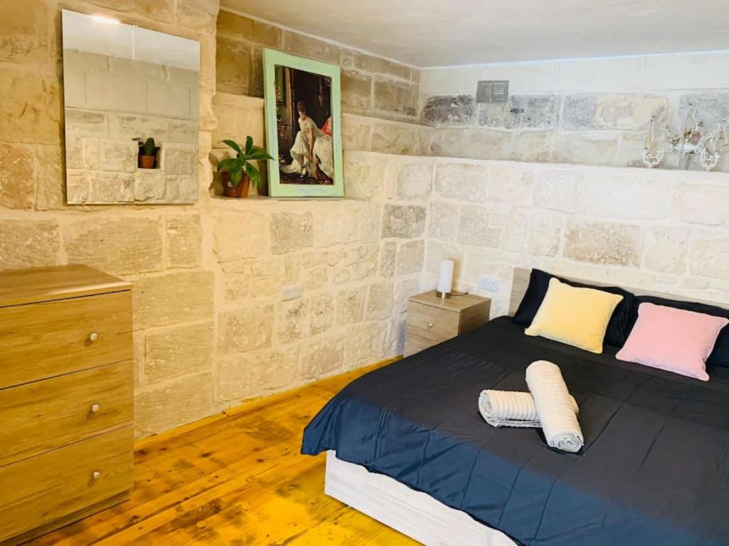 a bedroom with a king sized bed in a stone wall at Serenity in Qormi