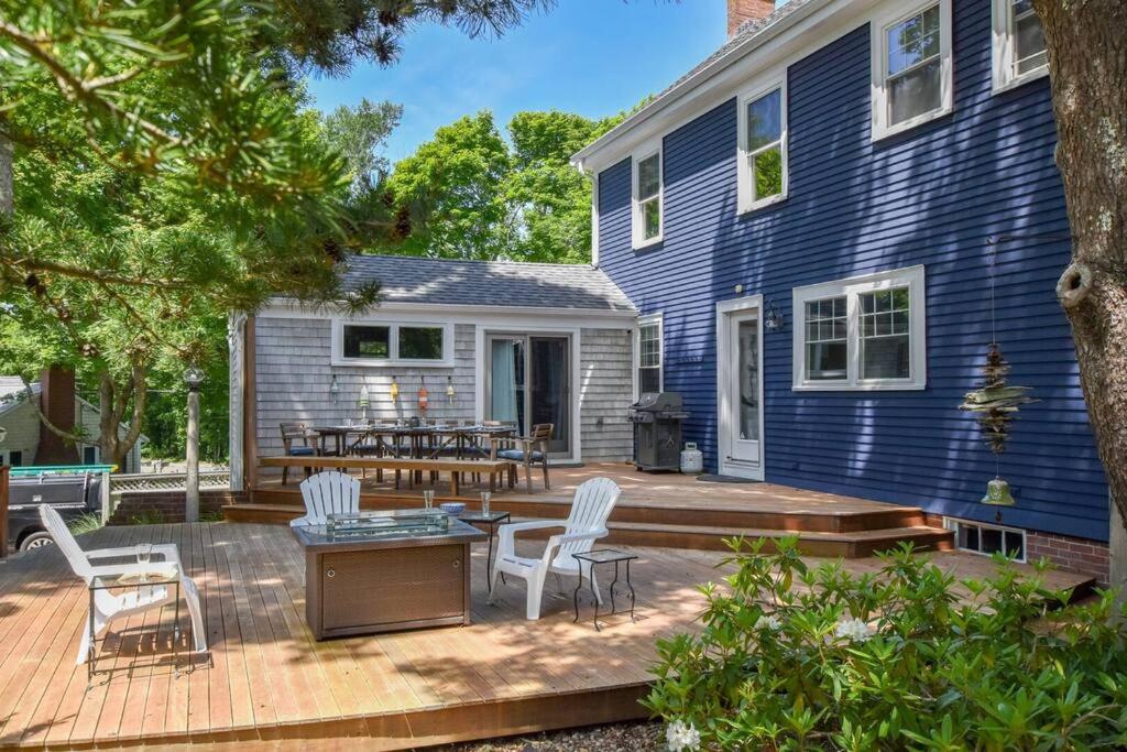a backyard with a wooden deck and a blue house at Beautifully Renovated in Harwich Center in Harwich