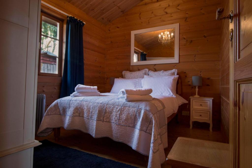 een slaapkamer met een bed in een blokhut bij tranquil log cabin in Shepton Mallet