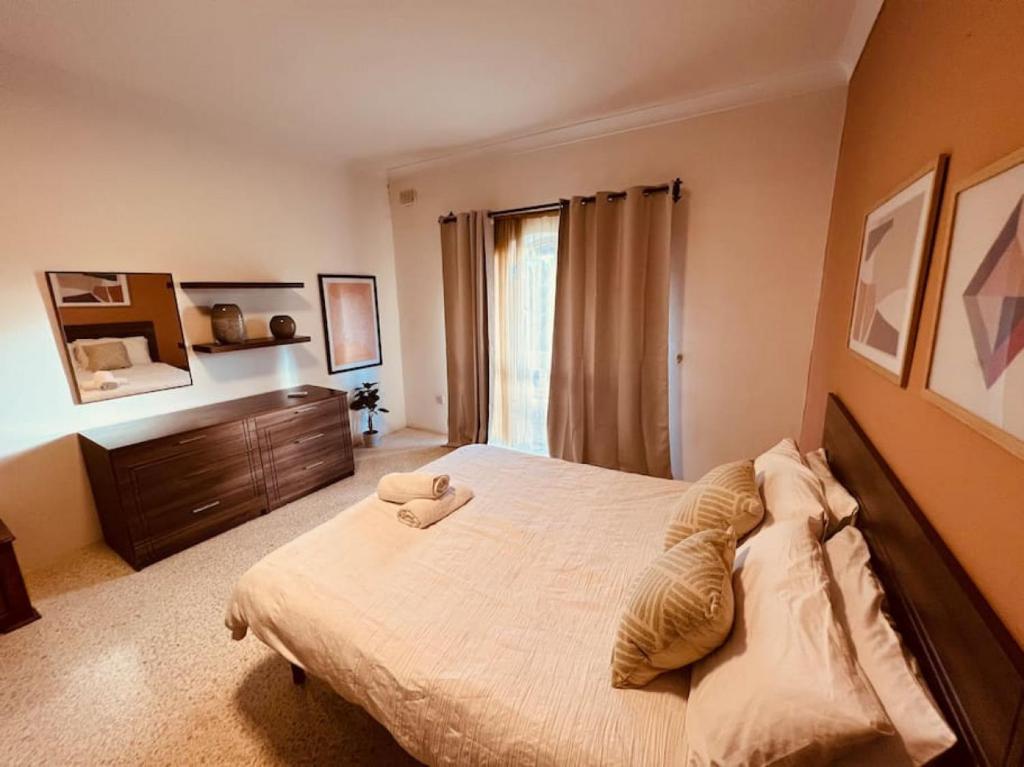a bedroom with a large bed and a dresser at Lovely 3 bedroom in Siggiewi in Siġġiewi