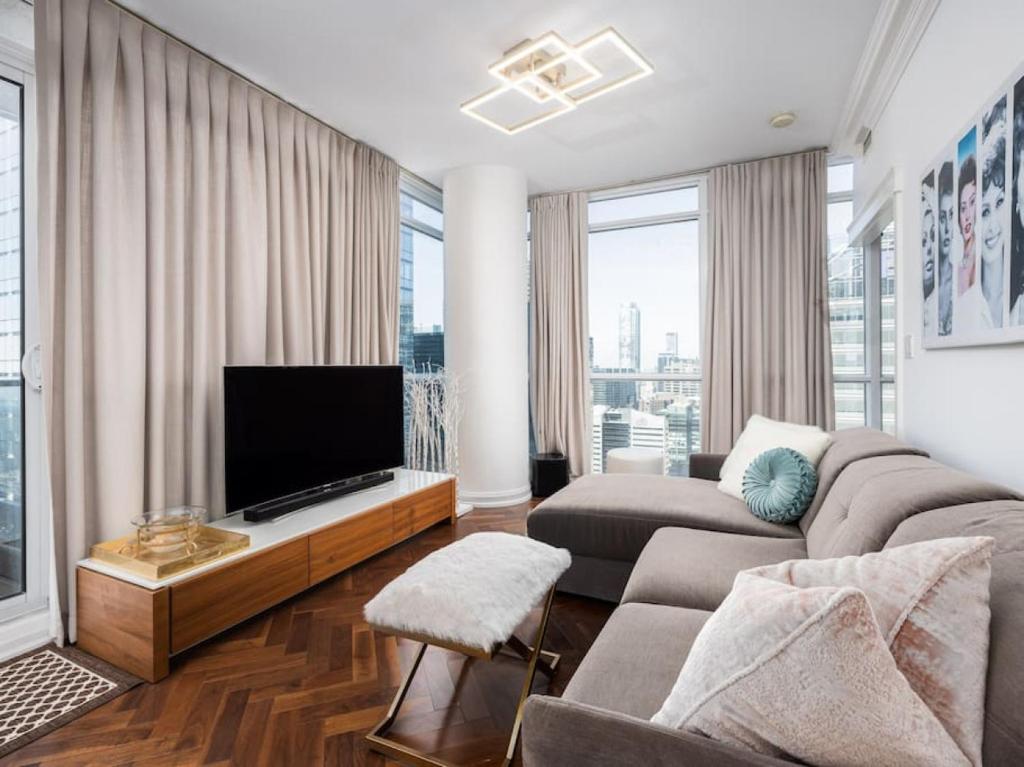 a living room with a couch and a flat screen tv at Pristine Modern 2BR Condo Private BBQ and Balcony in Toronto