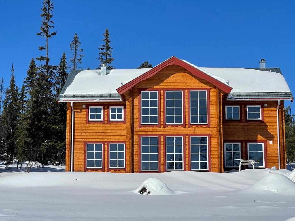 a house in the snow with a pile of snow in front at Vemdalsskalet huset Myltan in Vemdalen