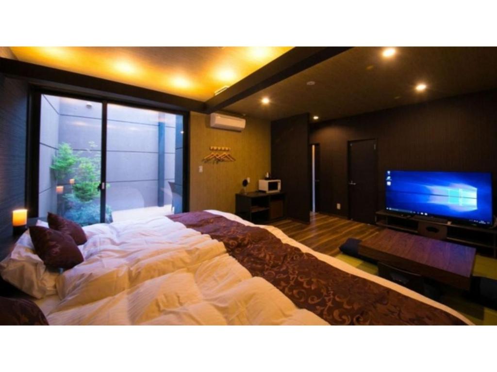 Oita Onsen Business Resort Sourin - Vacation STAY 73383v في أويتا: غرفة نوم بسرير كبير وتلفزيون بشاشة مسطحة