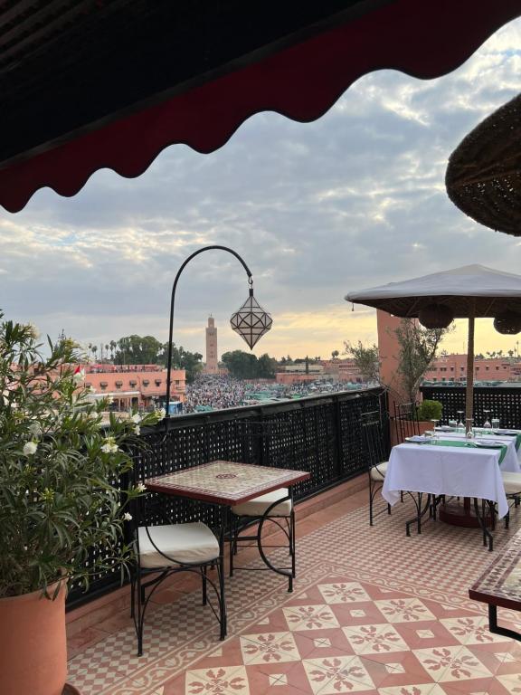 eine Terrasse mit Tischen und Stühlen und Stadtblick in der Unterkunft Riad Andalla in Marrakesch