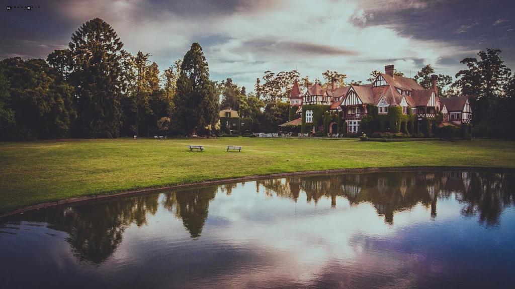 a large house with a pond in front of it at Estancia Villa Maria in Ezeiza