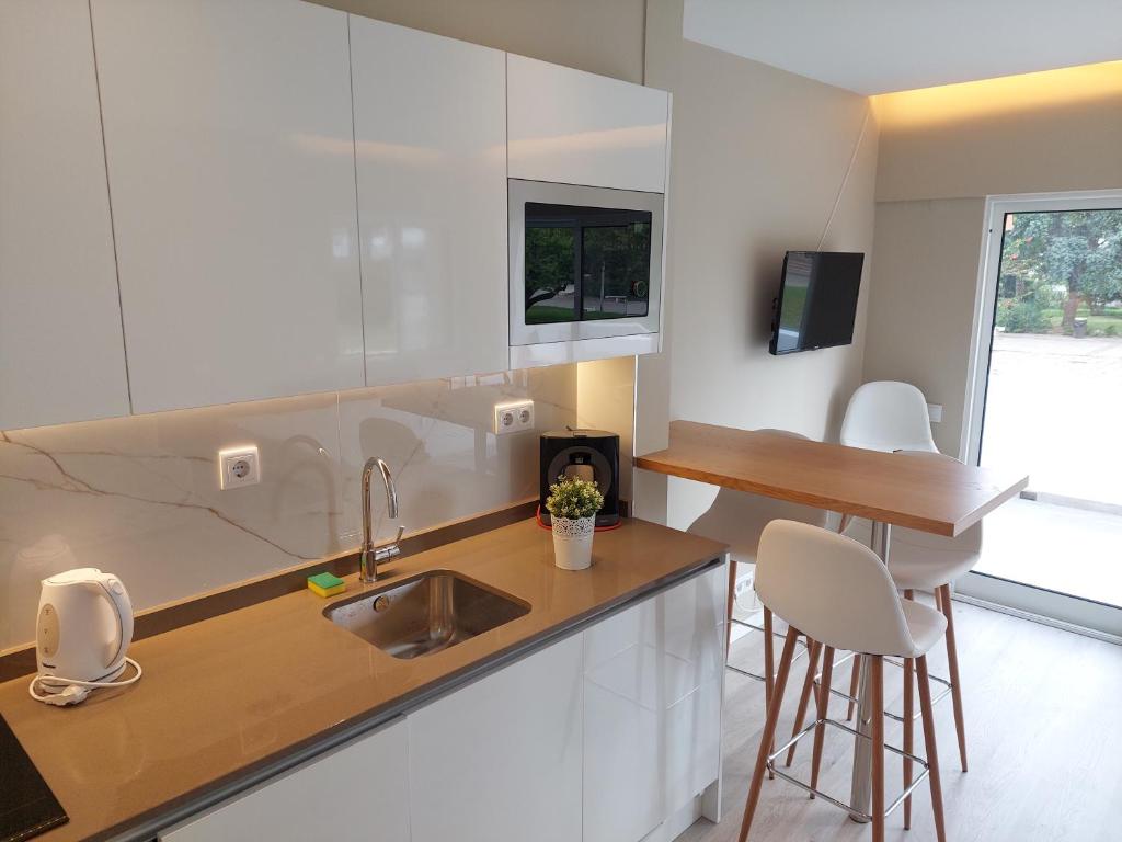 a kitchen with a sink and a counter with stools at Impervila 201 in Vilamoura