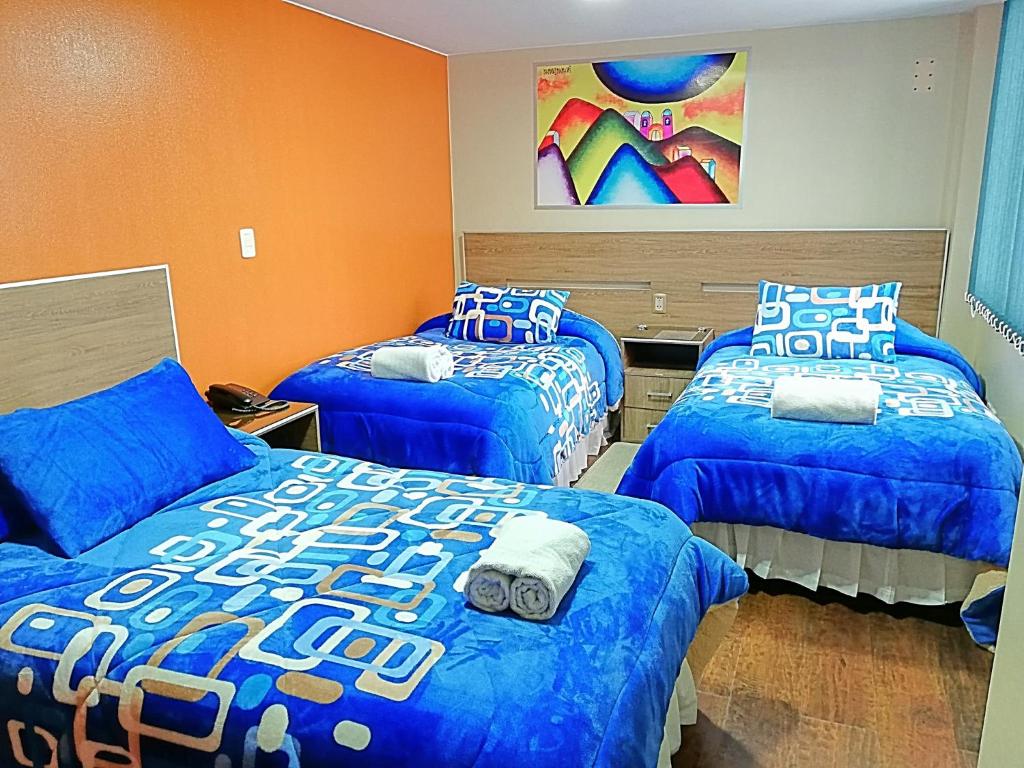 1 Schlafzimmer mit 3 Betten und blauen Bettdecken in der Unterkunft Hostal NAVAL in La Paz