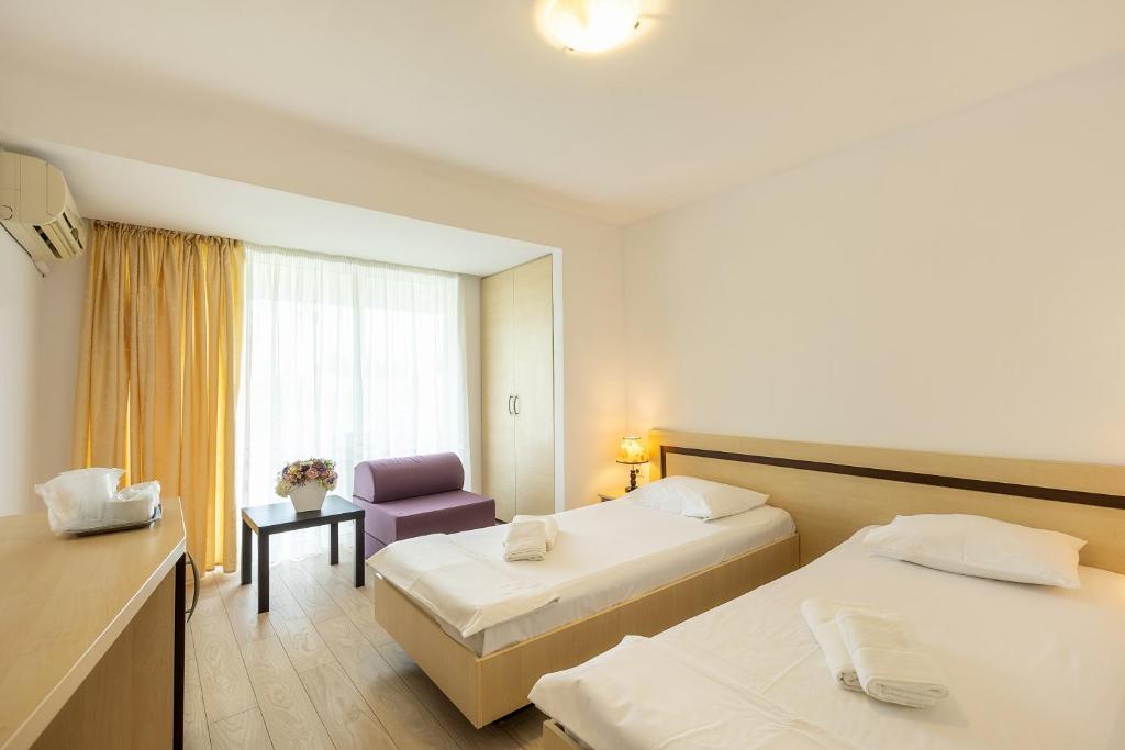 una habitación de hotel con 2 camas y una silla en Hotel Venus en Mamaia