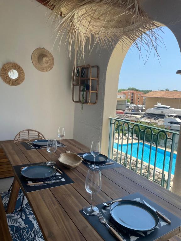une table en bois avec des verres et une vue sur une piscine dans l'établissement Appartement avec piscine, à Grimaud
