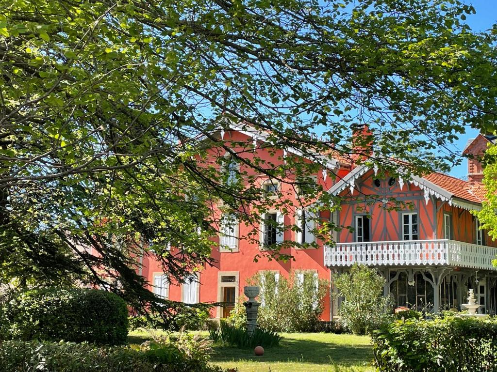 uma grande casa vermelha com um alpendre branco em Domaine La Belle Histoire - Gîte côté Parc em Besset