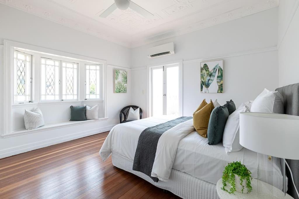 a white bedroom with a large bed and windows at Pet Friendly Family Home 3km to CBD in Brisbane