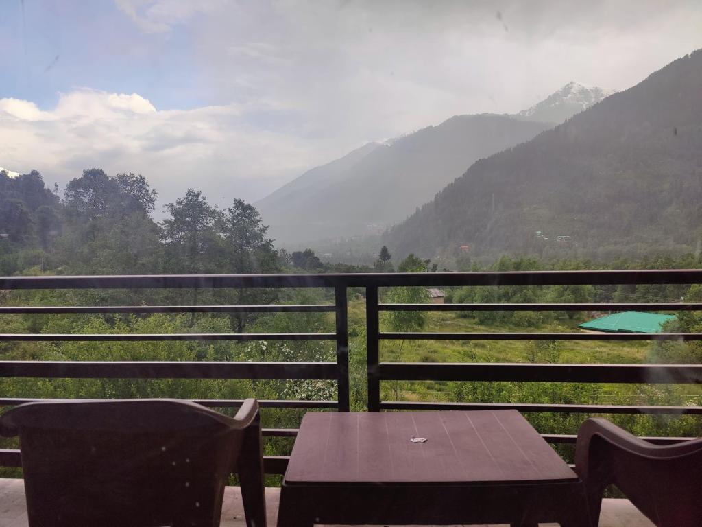 a table and chairs on a balcony with a view of mountains at Cabin in the Woods in Vashisht