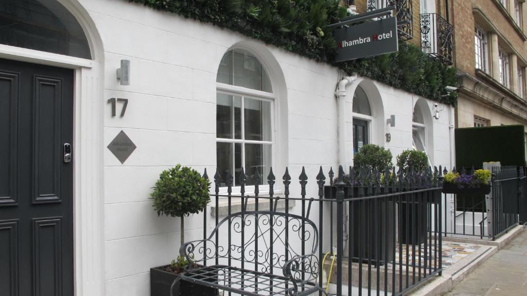 a white building with a black fence and potted plants at Alhambra Hotel in London