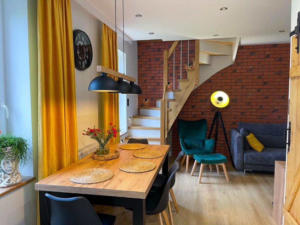 d'une salle à manger avec une table, des chaises et un mur en briques. dans l'établissement Apartament Kamienica Loft, à Kudowa-Zdrój