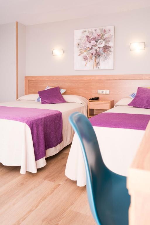 a hotel room with two beds and a blue chair at Hotel Caribe Sanxenxo in Sanxenxo